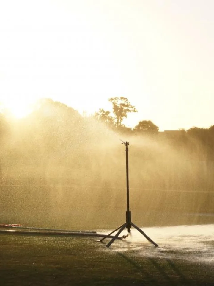 Garden sprinkler watering a lawn in early morning light